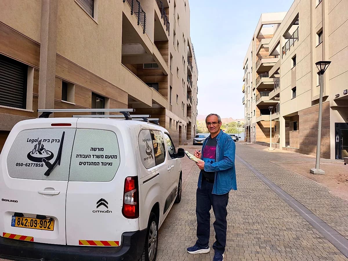 יגאל בנסקי, מומחה בדק בית מוסמך מטעם איגוד המהנדסים, ליד רכב השירות של בדק בית Legal בפרויקט מגורים חדש - בדק בית, איתור ליקויי בנייה ובדיקת דירה מקבלן