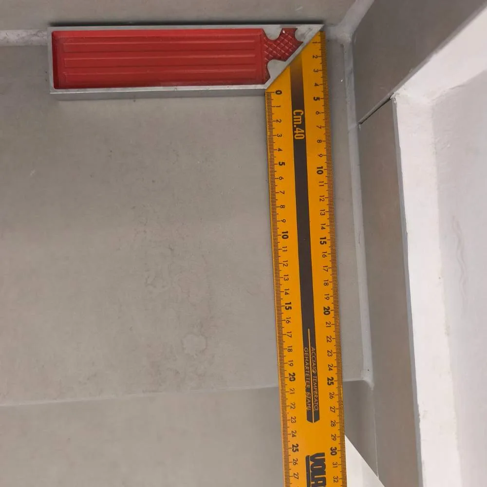 מדידת עומק שלח המדרגה סרגל זווית מונח על מדרגה בדירה ומודד את עומק השלח, שנמצא קטן מ-26 סנטימטר - סטייה מיחס רום שלח התקני שאותרה בבדק בית