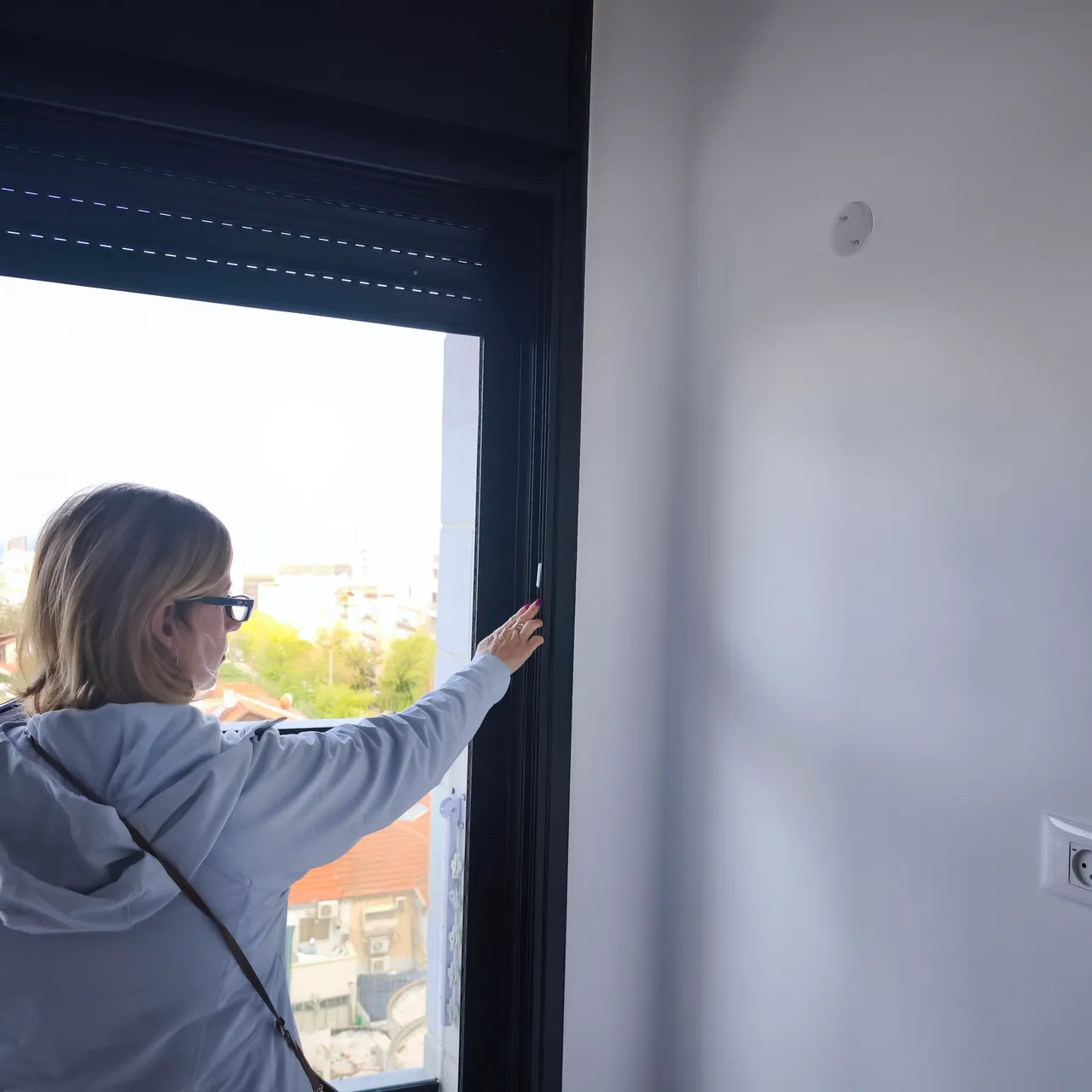 מומחית בדק בית בודקת תפקוד חלון, תריס ומסילה בדירה - איתור ליקויי התקנה ואיטום בחלונות בבדק בית