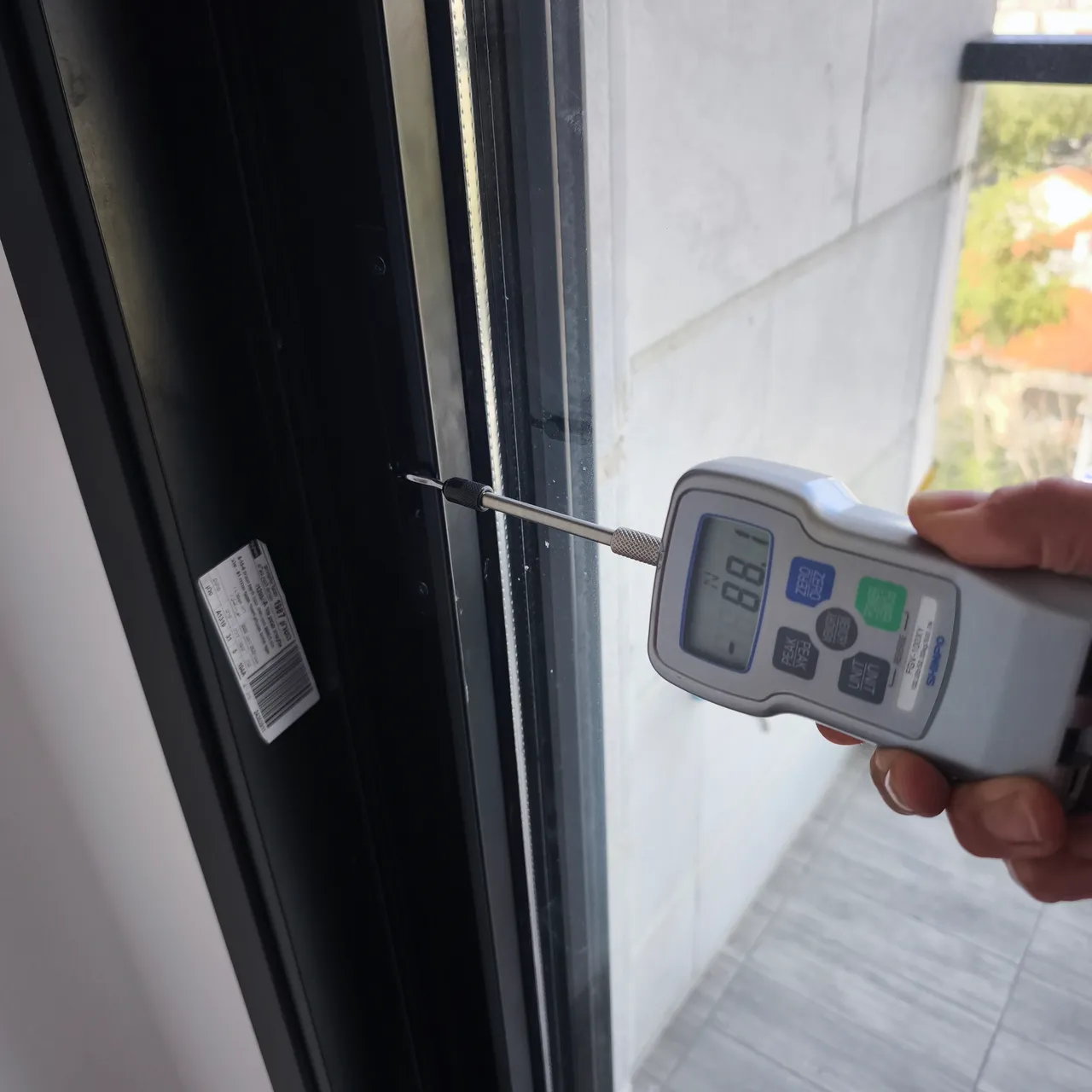 מדידת הכוח הנדרש להפעלת חלון בעזרת מד כוח דיגיטלי בבדק בית לדירה חדשה - בדיקת תקינות חלונות לפי תקן לפני מסירה