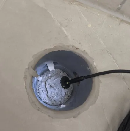פתח מחסום רצפה שנחשף ברצפת דירה, ובתוכו חומר בנייה שהתקשה ושאריות ניילון החוסמים את הניקוז - ממצא בבדק בית לדירה חדשה