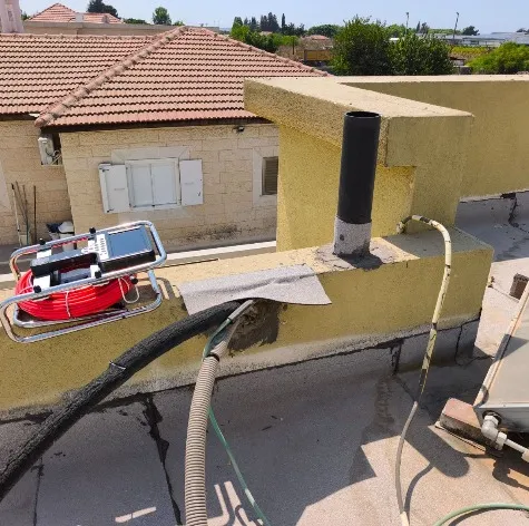 צינור אנכי פתוח בראש קיר מעקה בגג, ללא כיפוף מקל סבא וללא מכסה מגן מפני גשם, לצד סדק פתוח בקיר המעקה - ליקוי שמכניס מי גשם ישירות לצנרת ולמבנה